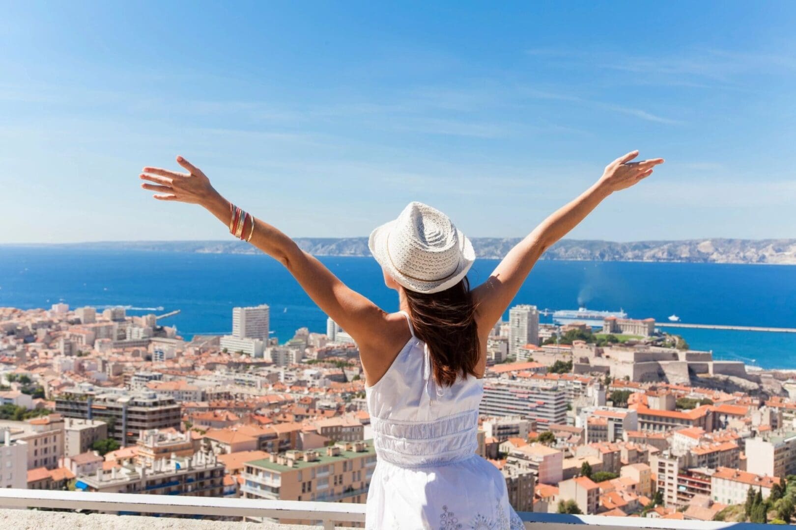 A woman in white shirt and hat standing on top of building.