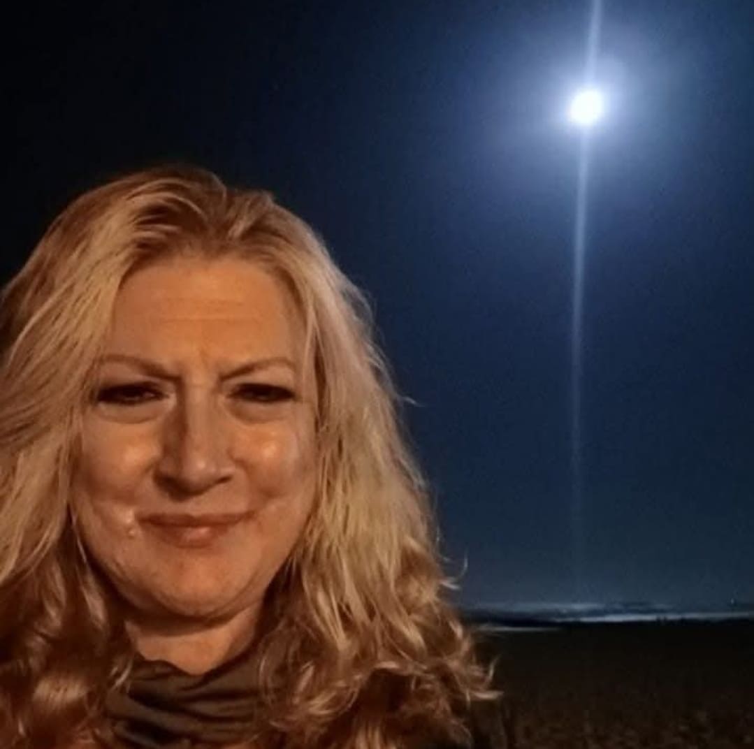 Woman smiling under bright night sky.
