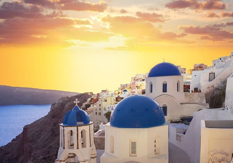 Santorini sunset with blue-domed buildings.