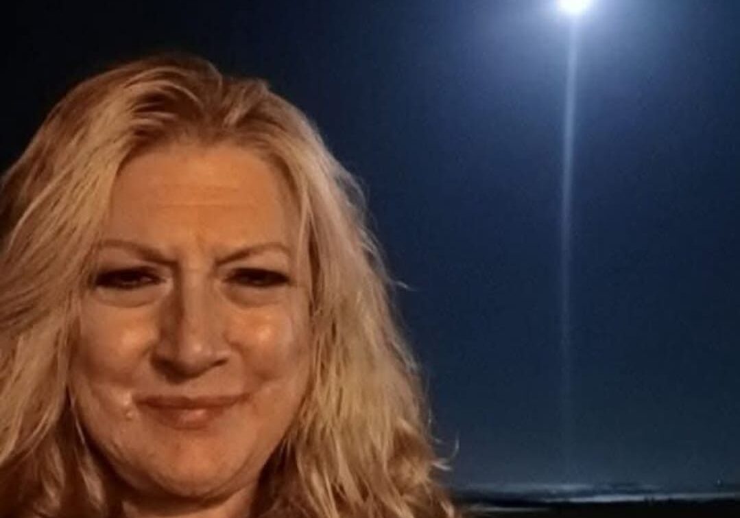 Woman smiling under bright night sky.