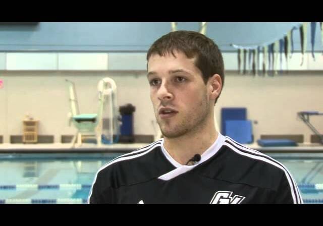 Man speaking in front of indoor pool.