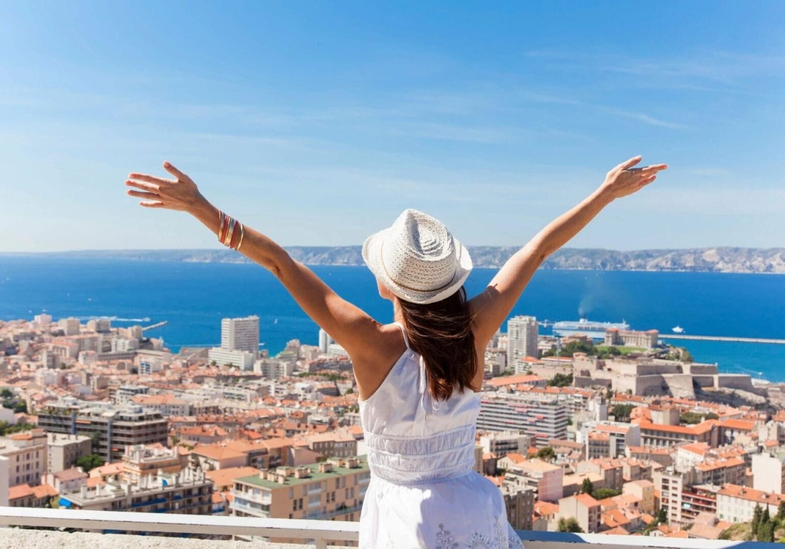 A woman in white shirt and hat standing on top of building.