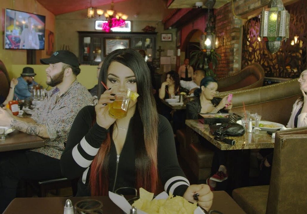Woman drinking in a busy restaurant.